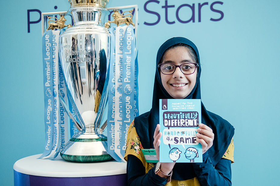 Key Stage 2 national winner Maariya standing next to the trophy holding up a copy of the writing stars poetry book